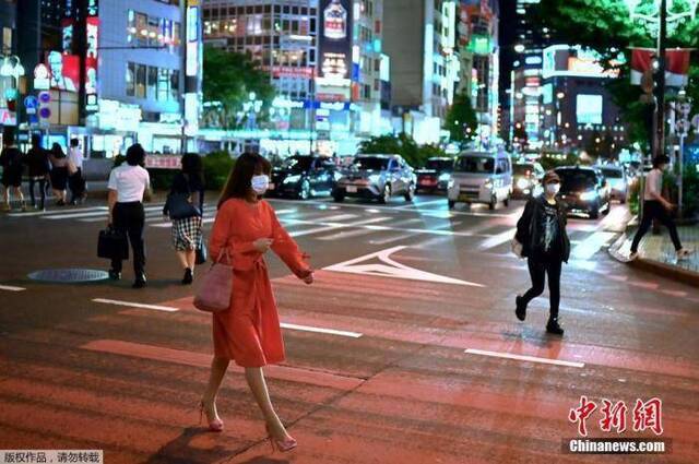 当地时间5月25日，日本东京新宿区，一名戴口罩的妇女穿过街道。