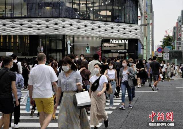当地时间6月6日，日本东京都发布新冠肺炎疫情“东京警报”后的首个周末，当地选择出门逛街的民众数量并没有大幅减少。图为当地民众佩戴口罩走过东京街头。中新社记者吕少威摄