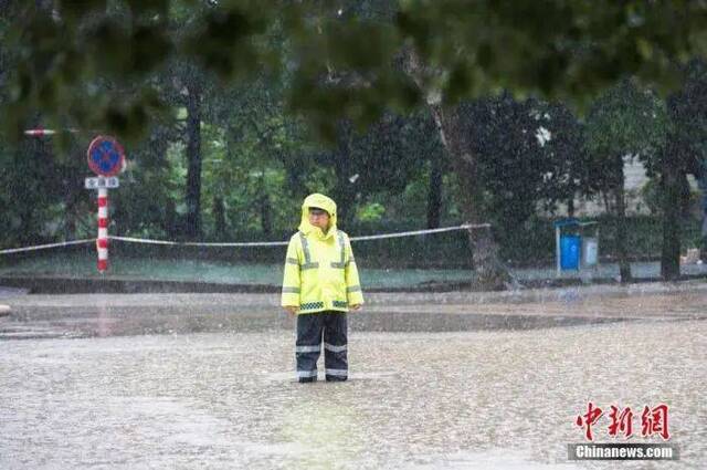 资料图：6月13日，浙江省金华市浦江县大雨倾盆，交警冒雨执勤，阻拦车辆进入漫水路段。中新社发张浩钺摄