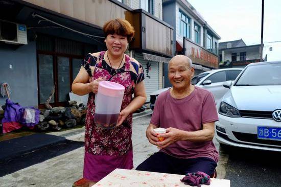 童松达和儿媳胡亚丽把烧好的酸梅汤端出家门，送给路人喝。