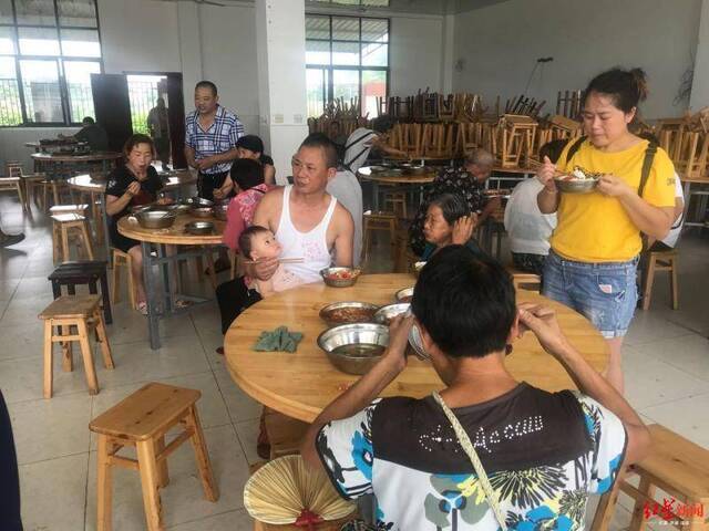 ↑村民在民兵训练基地安置点吃午饭。