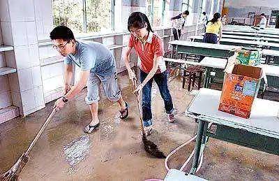 △图为2006年，学生清理考场中的淤泥准备迎接高考