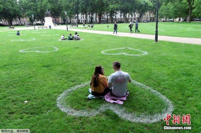 资料图：当地时间2020年7月8日，英国布里斯托尔，艺术家在皇后广场的草地上画出心形图案，敦促人们保持社交距离。