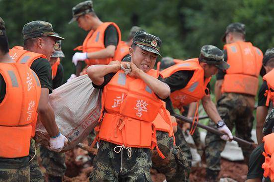 武警江西总队机动支队官兵奋战在上饶市鄱阳县江家岭村昌江圩堤坝，图为官兵正在搬运沙袋，加固堤坝。