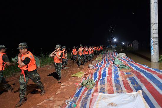 2020年7月11日，武警江西总队机动支队官兵在鄱阳县江家岭村昌江圩抗洪一线搬运沙袋。本文照片均由武警江西总队战士许书灿摄