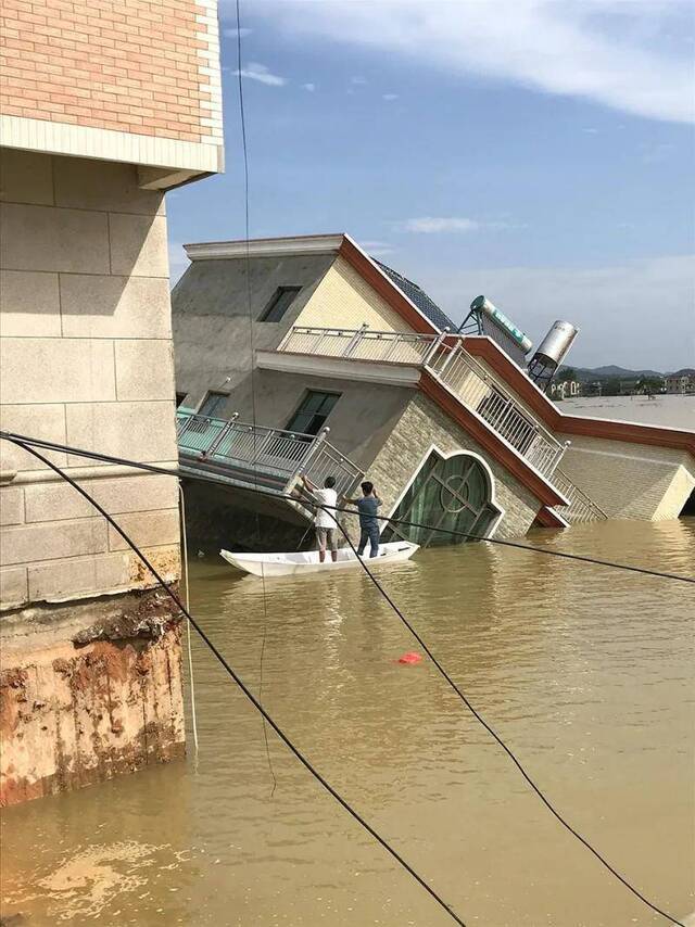 黄紫益和几个亲戚爬回倾斜的叔叔家房屋中收拾物资