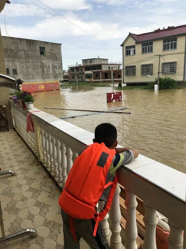 黄家一个孩子回到家中后，趴在二楼阳台上无奈地“看海”。