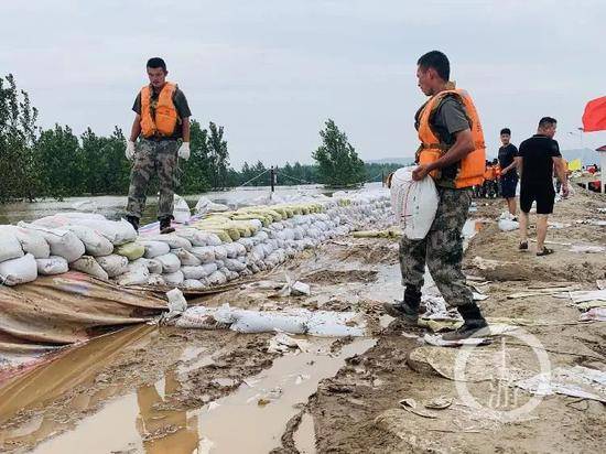  7月13日，江西九江市江洲镇，解放军和武警官兵在抗洪一线修筑防洪堤坝。/记者时婷婷