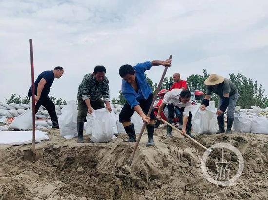  7月13日，江西九江市江洲镇，当地村民正在装沙袋堤坝修筑。/记者时婷婷