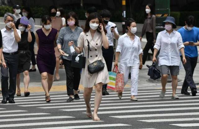 6月23日，戴口罩的行人在韩国首尔市中心过马路。韩国中央防疫对策本部本部长郑银敬22日表示，韩国首都圈地区正在经历新冠疫情的第二波扩散，要充分做好与疫情长期作战的准备。新华社/法新
