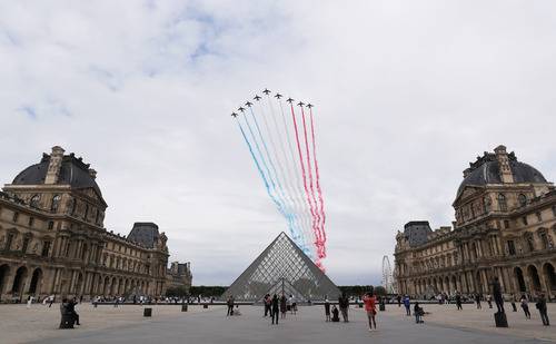 7月14日，“法兰西巡逻兵”飞行表演队飞过法国巴黎卢浮宫玻璃金字塔广场。新华社记者高静摄