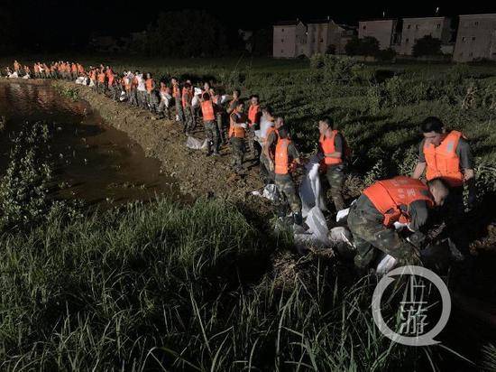 ▲7月15日晚，江西鄱阳油墩街镇东联圩发生管涌，火箭军部队官兵排起长龙，通过接力方式进行沙袋封堵作业。受访者供图