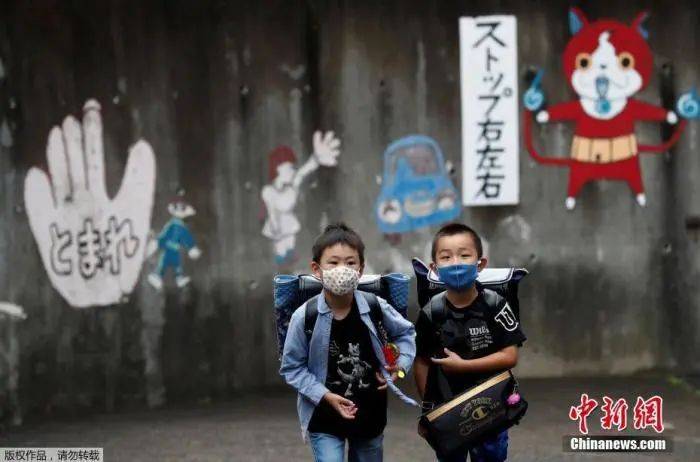 资料图：当地时间7月16日，日本东京，孩子们戴着口罩结伴上学。