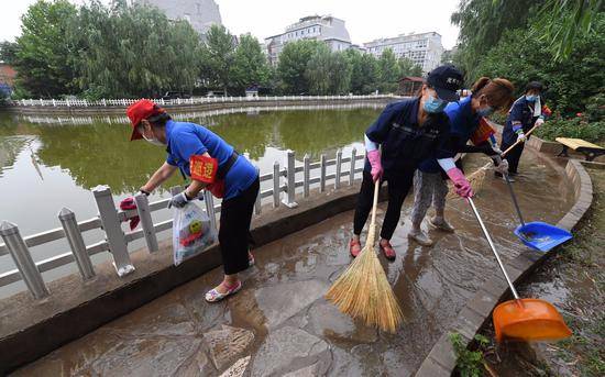 在丰台风格与林社区，社区工作人员、志愿者等对湖边路面进行清扫。丰台区委宣传部供图