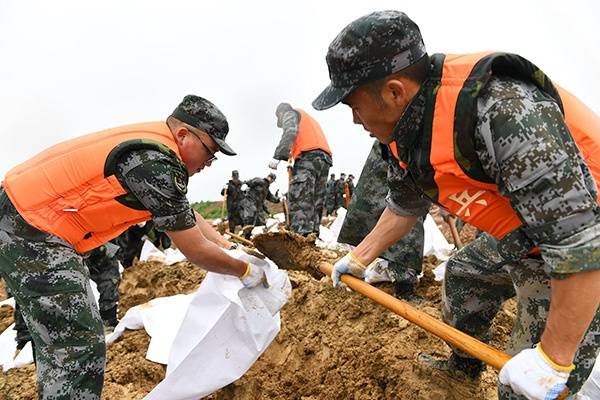 2020年7月19日，在合肥市庐江县同大镇同大圩，陆军炮兵防空兵学院学员正在装填沙袋、加固堤坝。人民视觉图