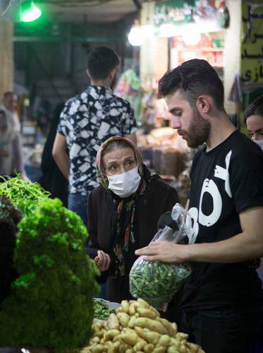  6月23日，一名佩戴口罩的老人在伊朗德黑兰购买蔬果。新华社发（艾哈迈德·哈拉比萨斯摄）