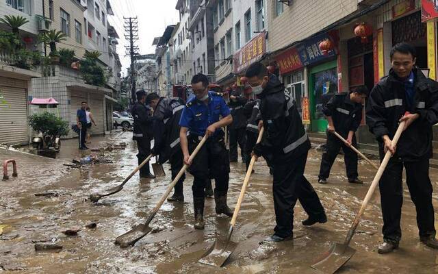 7月26日，建始县城区洪水过后，工作人员运走被淹车辆。新京报记者向凯摄