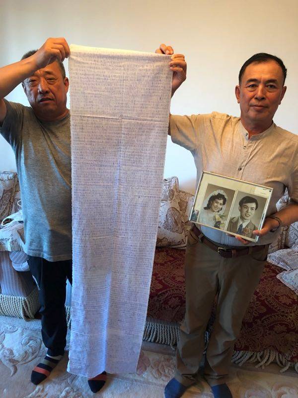 田志彬（左）和刘铁生手持田志娟在狱中写于布条上的家书