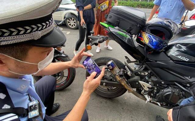 民警对违法改装的摩托车排气管进行拍照取证。摄影/新京报记者王贵彬
