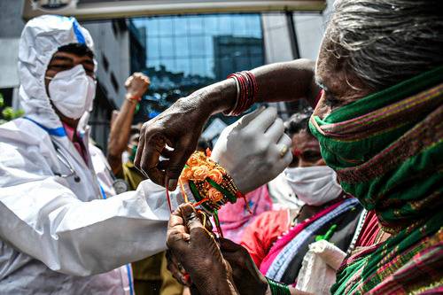  8月3日，一名女士在印度孟买将彩绳系在医护人员的手腕上。当天是印度的传统节日“保护绳节”。新华社发