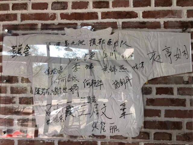 张永祥把签有19名医护工作者姓名的防护服挂在了农场办公室。