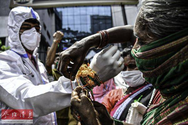 资料图片：8月3日，一名女子在印度孟买将彩绳系在医护人员的手腕上。（新华社发）