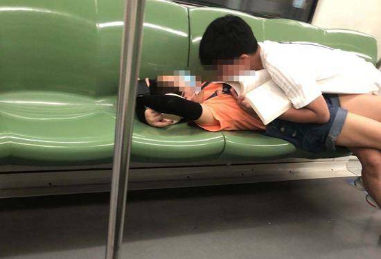 上海地铁1号线，一对男女躺卧在座椅上。本文图片@上海攻略君图