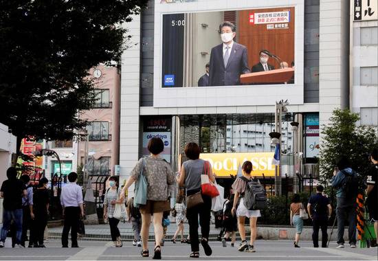 日本民众通过商场电子屏幕观看记者会