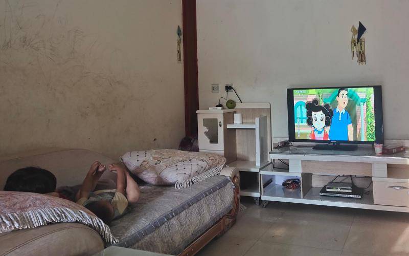 8月26日下午，回家后的圆圆正和欣欣躺在床上看电视。新京报记者马延君摄