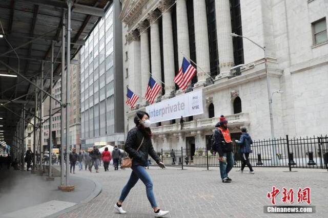 当地时间3月12日，一位戴口罩的民众走过纽约证券交易所。中新社记者廖攀摄
