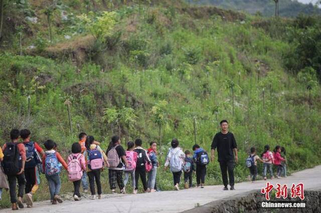 资料图：一名“90后”乡村教师组织学生排队上下学。中新社记者瞿宏伦摄