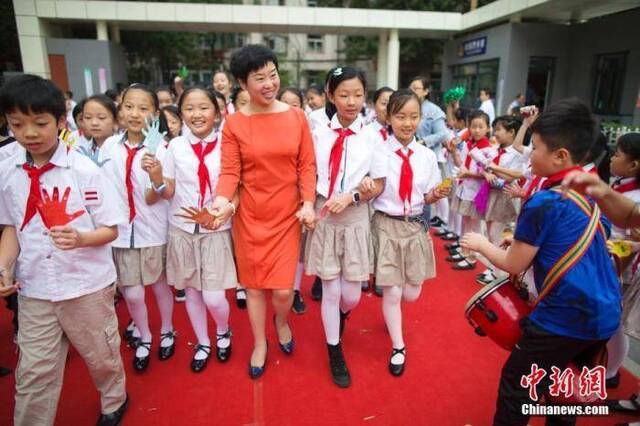 资料图：老师们牵着学生的手走过红地毯步入校园，并接受学生们的敬礼与祝福。张云摄