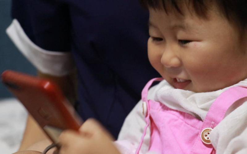 刘月的女儿田野在手机上和爸爸交流。新京报记者景如月摄