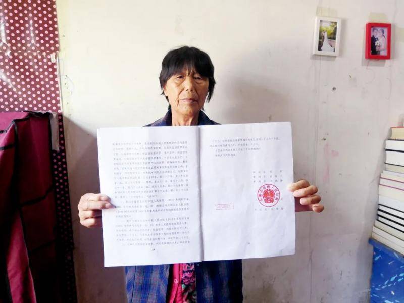 73岁的左德刚母亲陈英，打开安徽高院认定左不构成故意杀人的判决书。摄影/本刊记者周群峰