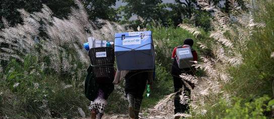 在2015年尼泊尔地震的震中Gorkha区，三位基层工作人员背着联合国儿童基金会提供的疫苗，深入地形复杂的区域进行疫苗接种工作。