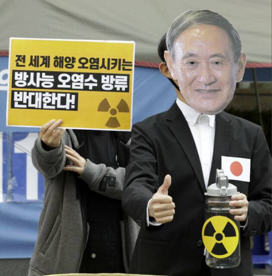 环保活动人士19日表演节目，称日本首相菅义伟认为手拿着福岛核污水是安全的。（韩民族日报）