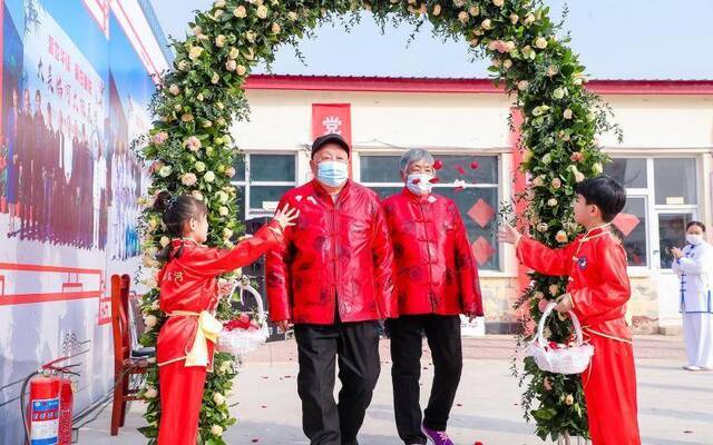 金婚老人在花童的带领下走过幸福花门。顺义区仁和镇供图