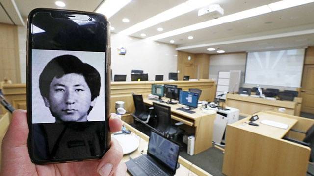 因无法拍摄李春宰本人，韩国记者手持资料照片进行报道。（韩联社）