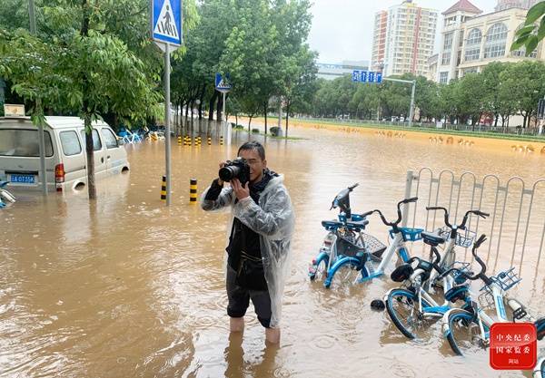 今年8月，云南省昆明市主城区不断发布暴雨橙色预警，城区内多处积水，记者冒雨报道街道积水情况。（云南省昆明市纪委监委供晓松摄）