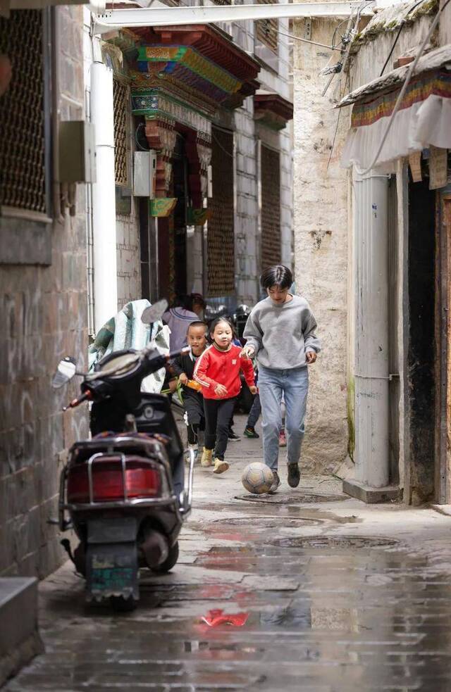 普布志玛（前）在拉萨八廓街街巷中和邻里街坊的孩子一起踢球（7月29日摄）。新华社记者晋美多吉摄