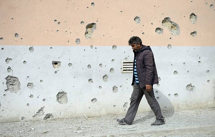 9月29日，在阿塞拜疆临近纳卡边境的塔塔尔地区，一名村民从布满弹孔的墙壁旁经过。新华社资料图