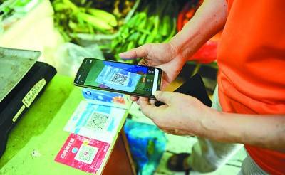 浙江杭州西湖区居民在果蔬店用手机支付买菜。新华社发