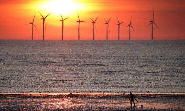 2018年5月22日，在英国新布赖顿，落日的余晖映衬着海上风力发电站机组。新华社/路透