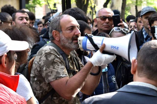 帕希尼杨2018年4月17日在一场反对政府的公共集会上。他手缠绷带，穿着迷彩上衣，模仿梅尔科尼扬的姿态对公众讲话。图源：commons.wikimedia.org