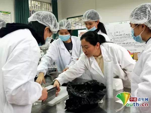 图为老师指导同学们如何处理原料鱼