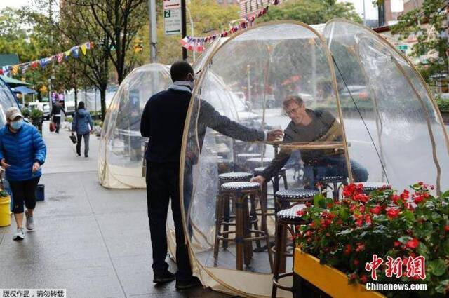 当地时间10月13日，纽约曼哈顿一家法式餐厅在户外布置“泡泡屋”以供顾客用餐，同时达到阻断病毒传播和避风保暖效果。中新社记者廖攀摄