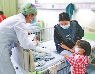 武汉儿童医院医务社工任军正在查房，花帽子是她不同于医护人员的标记。记者田巧萍摄