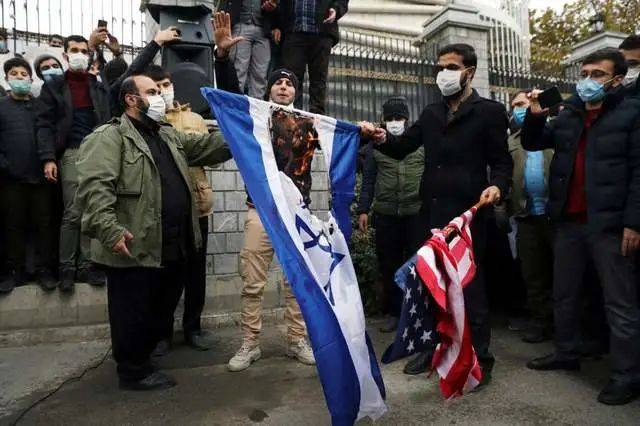 伊朗学生焚烧美国和以色列国旗。图源：法新社
