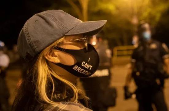 6月22日，一名女子戴着写有“我不能呼吸”的口罩在美国华盛顿白宫附近参加示威活动。新华社记者刘杰摄