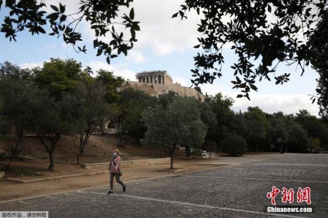 当地时间11月7日，希腊雅典，一名戴口罩女子经过帕特农神庙。